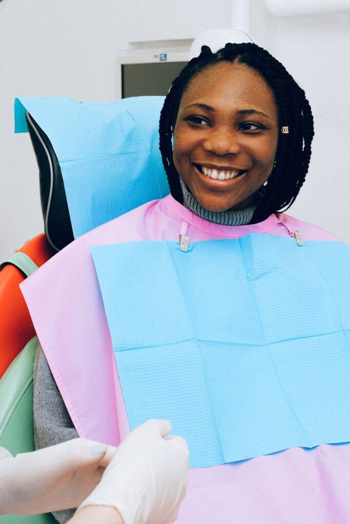 A smiling woman receives dental check-up from a practitioner in modern clinic.